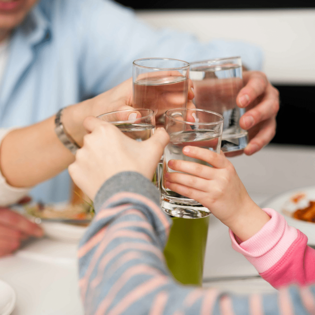 A family clinking glasses of water together at a meal