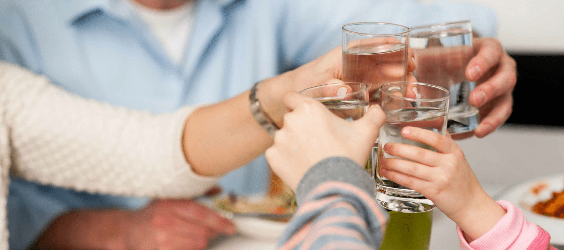 A family clinking glasses of water together at a meal